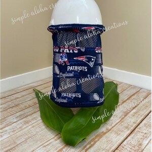 Pu&ograve; includere: Vista posteriore di un copricollo blu e bianco con un design dei New England Patriots. Il copricollo &egrave; realizzato in un tessuto traspirante e ha un pannello in rete per la ventilazione. Il testo "PATRIOTS" e "England" &egrave; visibile sul copricollo.