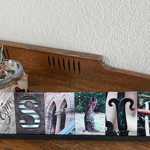 May include: A wooden sign with the word "SMITH" spelled out in individual tiles. Each tile features a different image, including a church, a tree, and a metal gate. The sign is on a wooden surface.