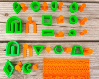 May include: A collection of green and orange geometric shapes, including arches, squares, and circles, along with a patterned orange rectangular stamp. The shapes are arranged on a light brown wooden surface.