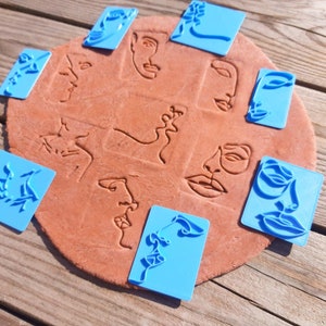 May include: Blue plastic stamps with different abstract face designs. The stamps are used to create impressions in clay or dough.