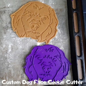 Könnte beinhalten: Ein brauner Keks und ein lila Ausstecher in Form eines Hundegesichts. Der Ausstecher ist aus Kunststoff. Der Text "Custom Dog Face Cookie Cutter" befindet sich am unteren Rand des Bildes.