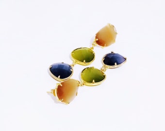 May include: A pair of long gold earrings with three teardrop-shaped stones. The stones are a gradient of green, blue, and brown.