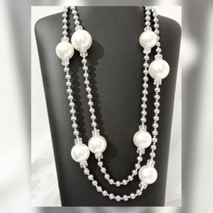 May include: A double strand pearl necklace with silver beads and large white faux pearls. The necklace is displayed on a black mannequin bust.