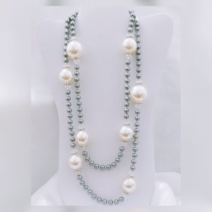 May include: A two-strand pearl necklace with grey beads and large white faux pearls. The necklace is displayed on a white mannequin bust.