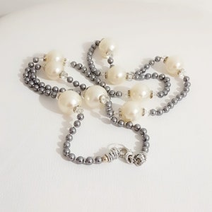 May include: A long grey pearl necklace with large white pearl beads and silver accents.
