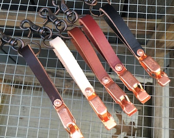 May include: Five leather keychains with copper key rings and clips. The keychains are in various colors, including black, brown, red, white, and cream.