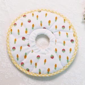 Puede incluir: Collar de recuperaci&oacute;n para mascotas blanco con un estampado de zanahorias naranjas y fresas rojas. El collar tiene un ribete de cuadros amarillos y un centro blanco suave.