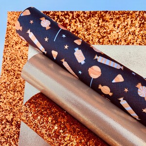 May include: A set of four craft supplies featuring a black fabric with a white and orange candy pattern, a gold glitter fabric, a copper glitter fabric, and a gold metallic fabric.
