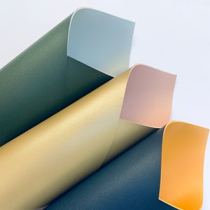 May include: Four sheets of faux leather in different colors: dark green, gold, light pink, and orange. The sheets are folded in a fan shape, revealing the different colors.