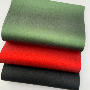 Op de afbeelding: Drie vellen getextureerd papier in groen, rood en zwart. Het groene vel ligt bovenaan, gevolgd door het rode en dan het zwarte. Het papier heeft een subtiele, gespikkelde uitstraling.