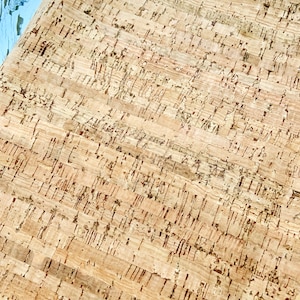 May include: A close-up of a sheet of cork with a natural brown color and a textured surface. The cork has a pattern of small, irregular shapes.