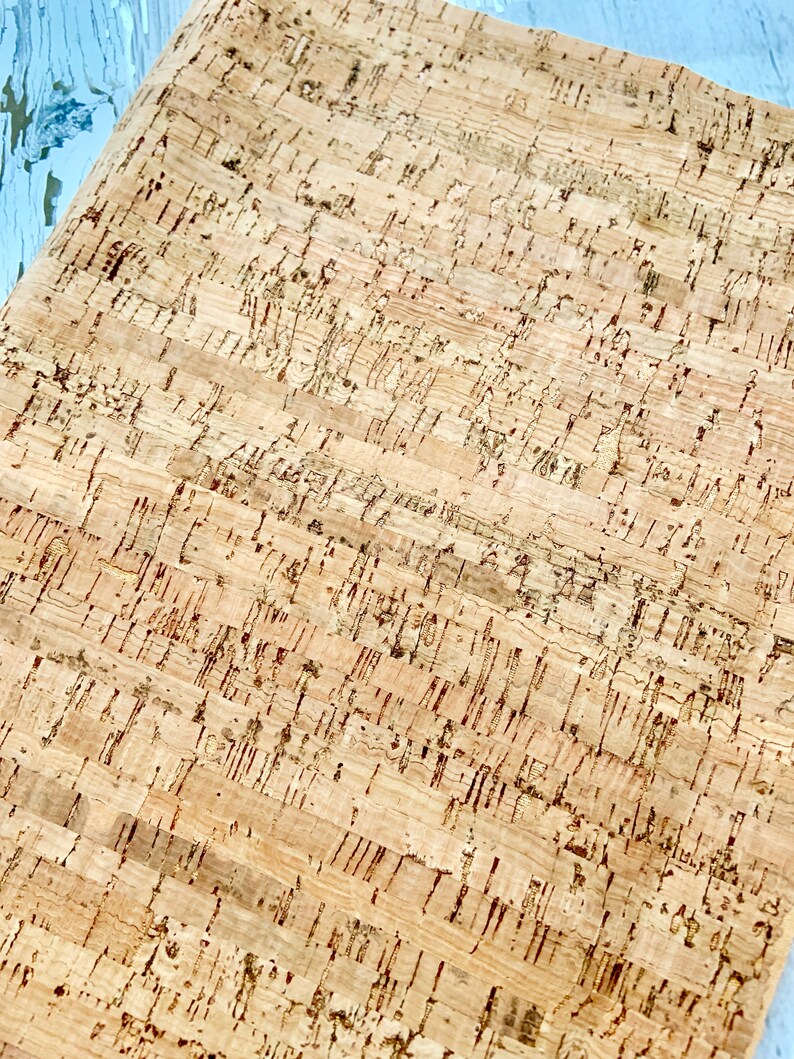 May include: A close-up of a sheet of cork with a natural brown color and a textured surface. The cork has a pattern of small, irregular shapes.