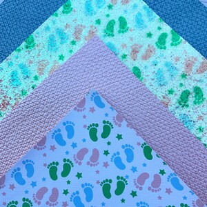 May include: Three fabric swatches, one with a blue glitter pattern, one with a pink leather texture, and one with a white background and a repeating pattern of green and blue footprints and stars.