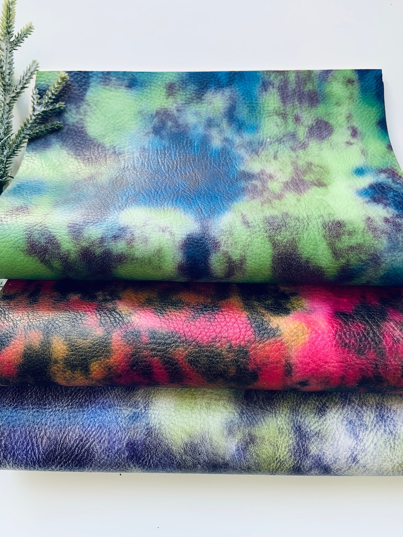 Puede incluir: Tres piezas de cuero sint&eacute;tico tie-dye en colores verde, rojo y azul. El cuero tiene una superficie texturizada.