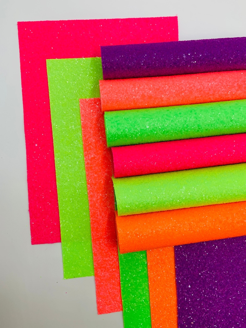 Pu&ograve; includere: Un mucchio di otto fogli di tessuto glitterato in vari colori neon, tra cui rosa, verde, arancione e viola.
