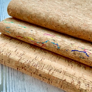 May include: Three sheets of cork fabric, one with a natural finish and two with colorful lines running through the cork.