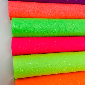 Pu&ograve; includere: Un rotolo di tessuto glitterato in sei diversi colori neon, tra cui viola, arancione, verde, rosa, verde lime e arancione.