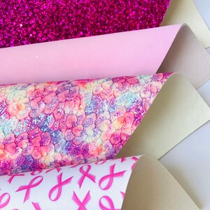May include: Four sheets of pink and white patterned faux leather. The top sheet is a sparkly pink, the second sheet is a solid light pink, the third sheet has a pink and white tie-dye pattern with pink ribbons, and the bottom sheet has a white background with pink ribbons.