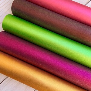K&ouml;nnte beinhalten: F&uuml;nf Rollen irisierendes Glitzer-Vinyl in verschiedenen Farben: Gold, Burgunder, Lila, Gr&uuml;n und Braun. Das Vinyl ist strukturiert und hat einen metallischen Glanz.