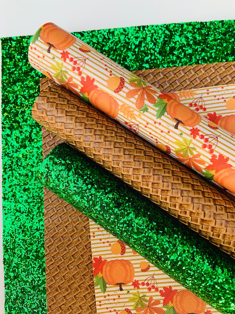 May include: An assortment of fall-themed craft materials. Rolls of patterned faux leather with pumpkins, leaves, and acorns, alongside textured brown and green glitter sheets. Ideal for seasonal crafting projects.