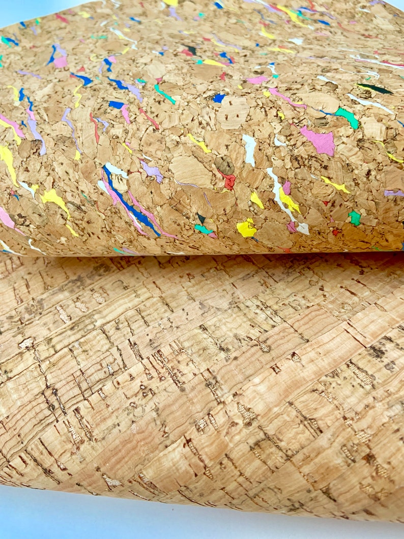 May include: Two pieces of cork fabric, one with a natural brown color and the other with a brown background and colorful flecks and streaks.