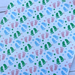 May include: White fabric with a repeating pattern of green, blue, and pink footprints and blue stars.