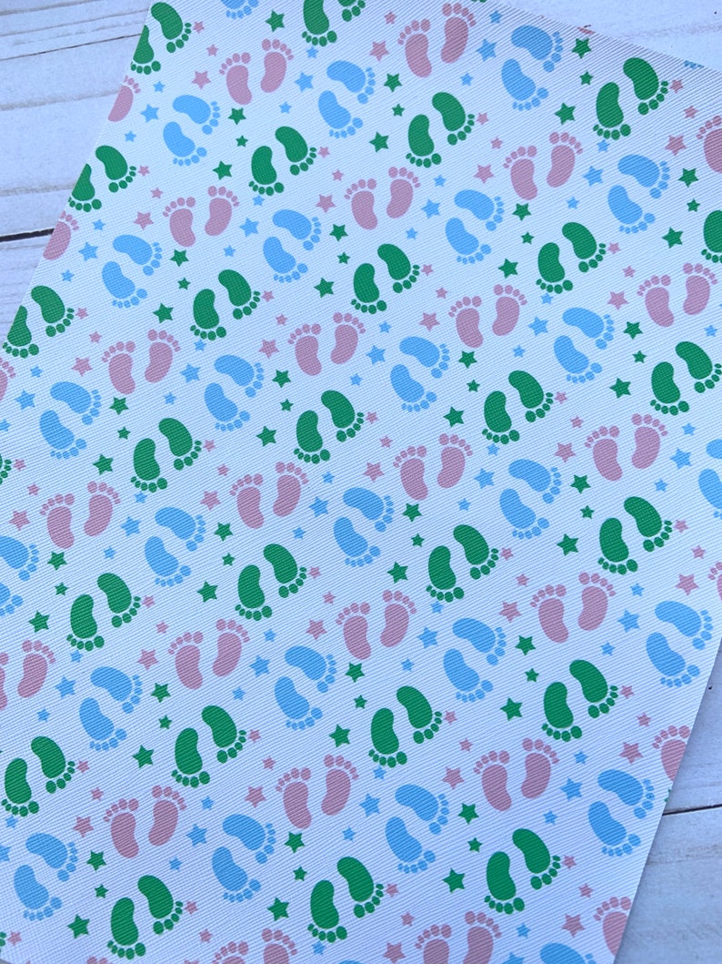 May include: White fabric with a repeating pattern of green, blue, and pink footprints and blue stars.