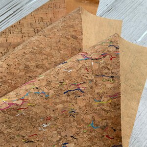 May include: Three sheets of cork fabric, one plain, one with a subtle texture, and one with colorful lines. The cork fabric is a natural material with a brown color.