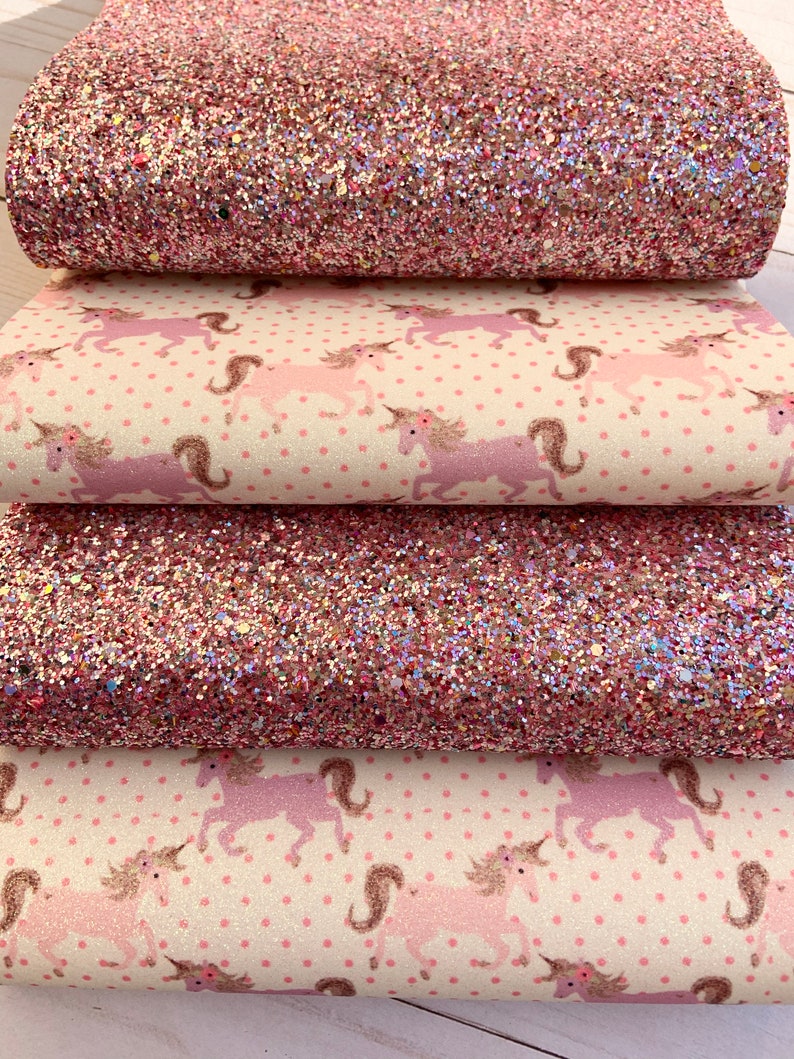 May include: Four pieces of pink and white fabric with a unicorn pattern. The top two pieces are pink glitter fabric. The bottom two pieces are white fabric with pink unicorns and pink polka dots.