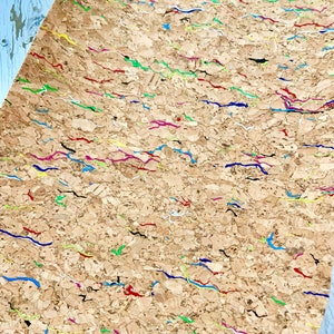 May include: A sheet of cork with a textured surface and colorful lines painted on it. The lines are in various colors, including red, blue, green, yellow, and pink.