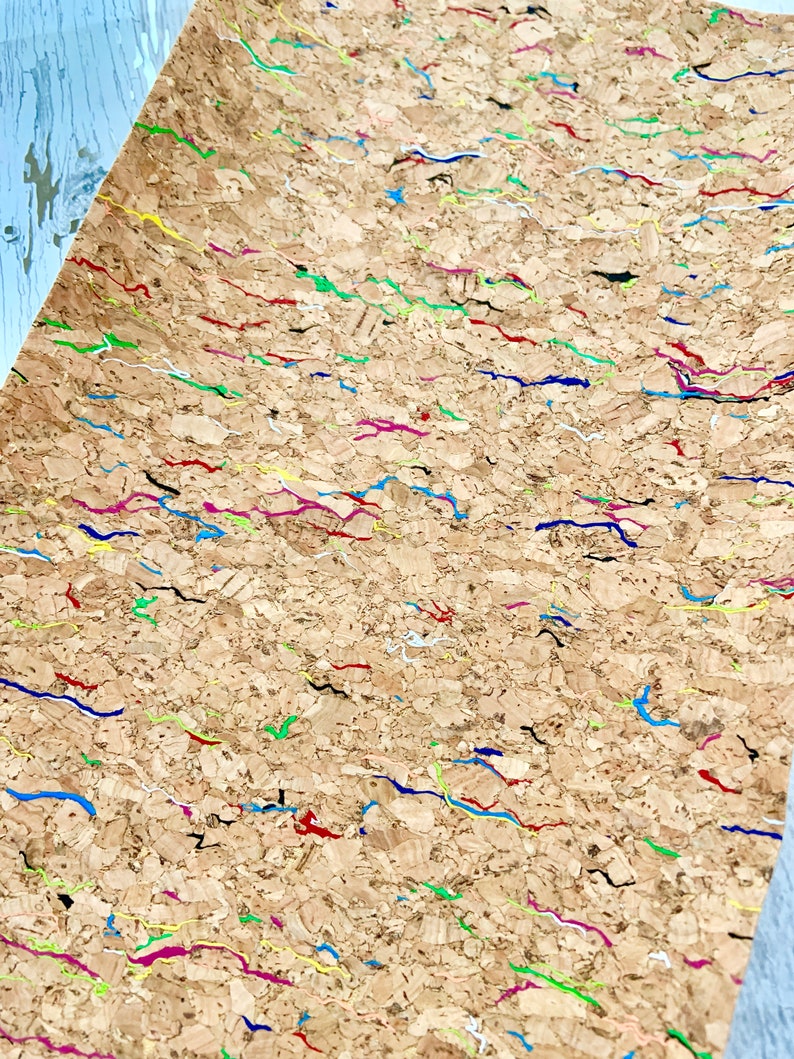 May include: A sheet of cork with a textured surface and colorful lines painted on it. The lines are in various colors, including red, blue, green, yellow, and pink.