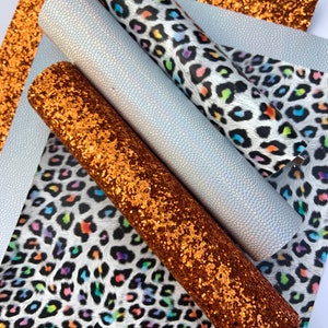 May include: Four sheets of faux leather in different patterns and colors. One sheet is a white faux leather with a subtle textured pattern. Another sheet is a white faux leather with a rainbow leopard print. The third sheet is a copper glitter faux leather. The fourth sheet is a copper glitter faux leather.