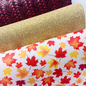 May include: Three fabric swatches, one with a red woven pattern, one with a gold glitter finish, and one with a white background and a red and yellow maple leaf pattern.
