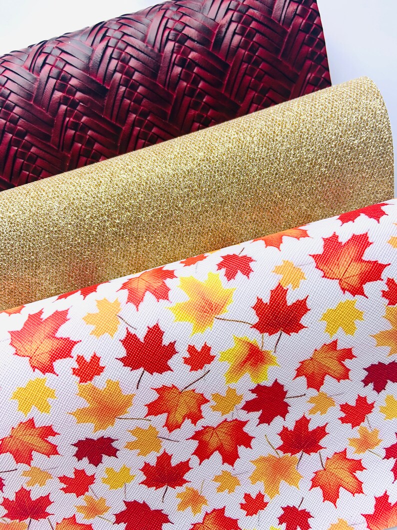 May include: Three fabric swatches, one with a red woven pattern, one with a gold glitter finish, and one with a white background and a red and yellow maple leaf pattern.