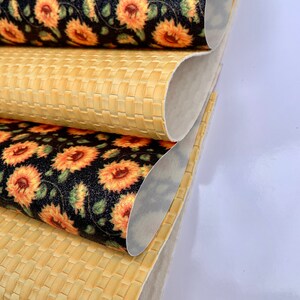 May include: Three rolls of fabric, one with a woven pattern and two with a sunflower print on a black background.