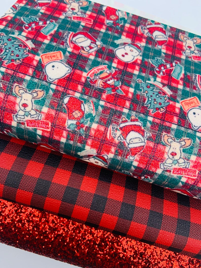 May include: Three sheets of red and black patterned fabric. The top sheet features a Christmas theme with a red and green plaid background and various holiday characters. The middle sheet is a red and black buffalo plaid. The bottom sheet is a red glitter fabric.
