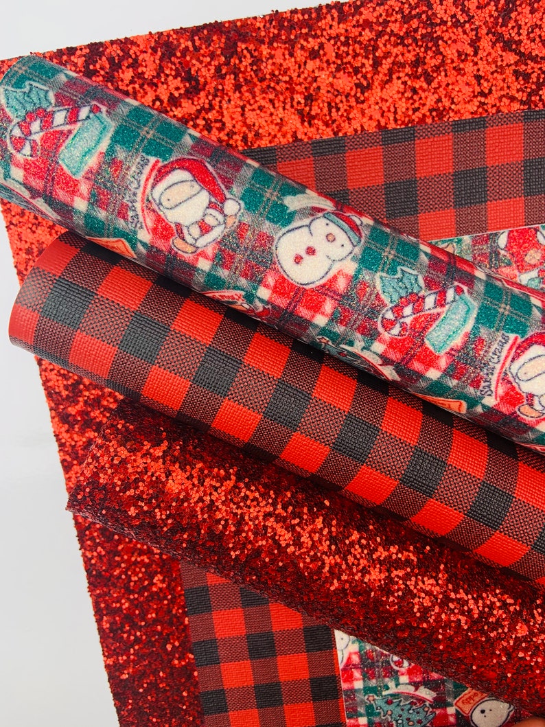 May include: Three sheets of fabric with a Christmas theme. The top sheet is red glitter fabric. The middle sheet is red and black buffalo plaid fabric. The bottom sheet is a white background with a red, green, and white Christmas pattern.