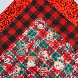 May include: Red and black buffalo plaid fabric with a red glitter fabric and a red and green plaid fabric with a Christmas theme featuring Santa, reindeer, snowmen, and Christmas trees.