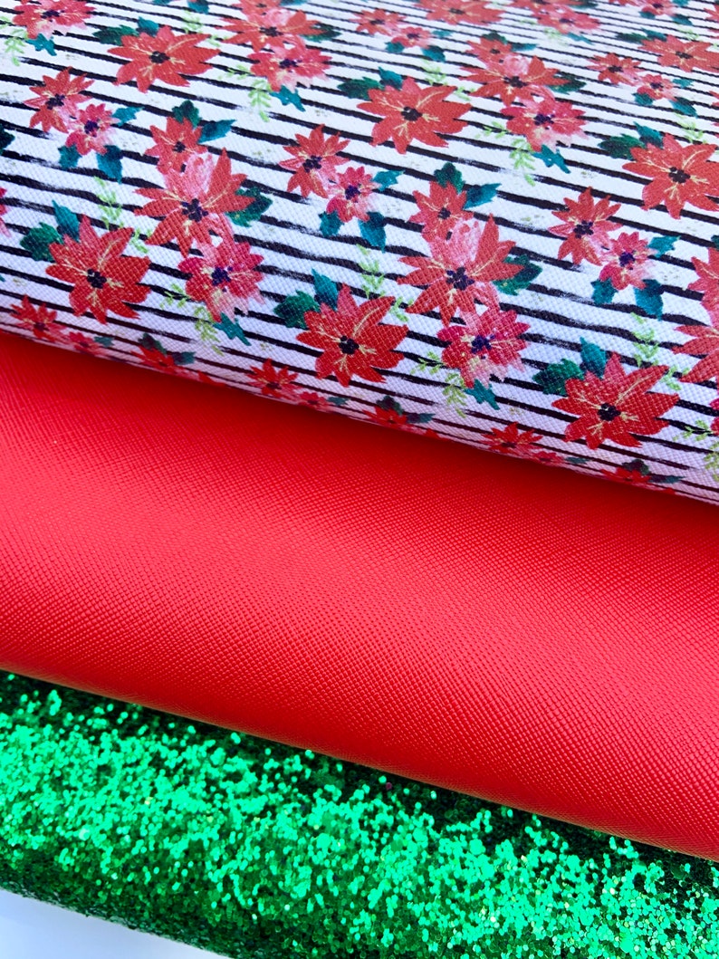 May include: A stack of three fabric sheets. The top sheet is white with black stripes and a red floral pattern. The middle sheet is a solid red. The bottom sheet is green glitter.