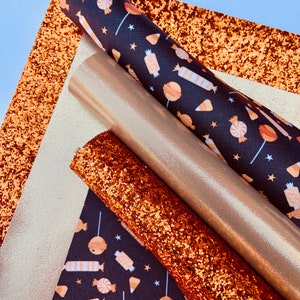May include: A set of four fabric sheets in various textures and colors. The sheets include a black fabric with a white and orange candy pattern, a gold glitter fabric, a copper glitter fabric, and a gold metallic fabric.