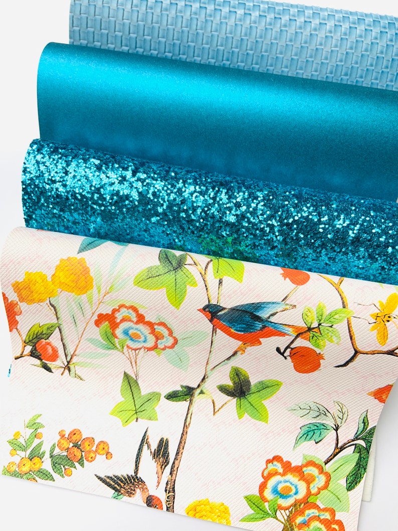 May include: A set of four teal fabric sheets with different textures. The top sheet has a woven pattern, the second sheet is a solid colour, the third sheet has a glitter finish, and the bottom sheet has a floral print with birds.