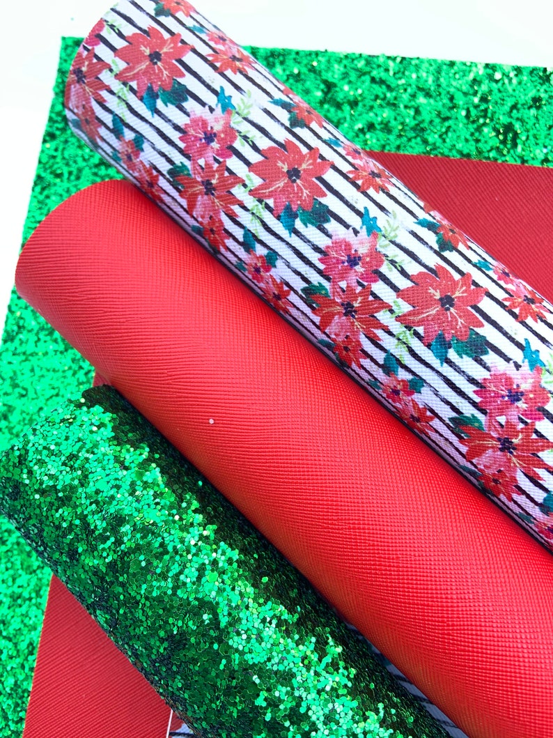 May include: Three sheets of fabric for crafting projects. One sheet is red, one is green glitter, and one is white with black stripes and a red floral pattern.