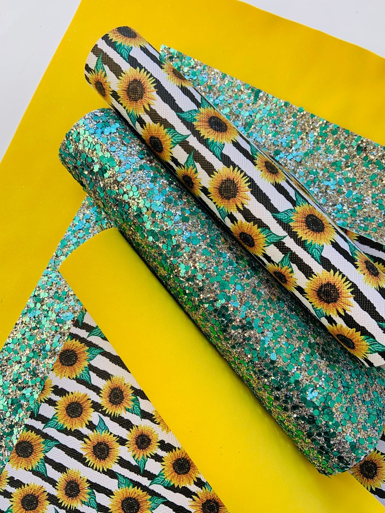 May include: Three sheets of fabric with a sunflower pattern. One sheet is black and white stripes with yellow sunflowers, another is green glitter, and the last is yellow.