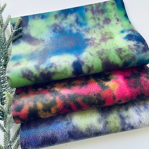 Puede incluir: Tres piezas de tela con patrones de tie-dye en verde, rosa y azul.