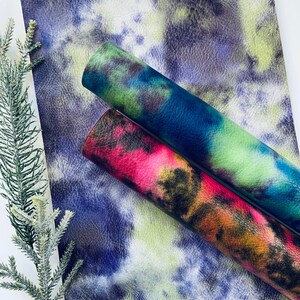 Puede incluir: Dos hojas de piel sint&eacute;tica con un patr&oacute;n de tie-dye. Una hoja es azul, verde y negra. La otra hoja es roja, naranja y negra.