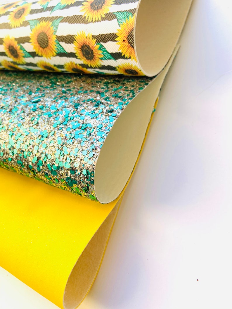 May include: Three rolls of fabric, one with a sunflower pattern, one with green and silver glitter, and one solid yellow.