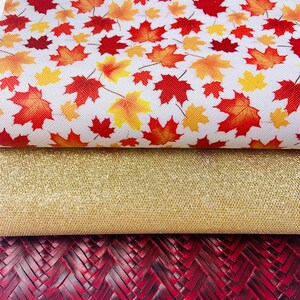 May include: Three pieces of fabric: a white fabric with a red and yellow leaf pattern, a gold glitter fabric, and a dark red woven fabric.