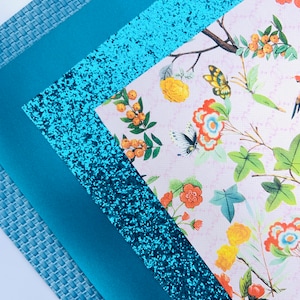 May include: Four sheets of turquoise blue craft paper. One sheet has a woven texture, one is solid, one is glitter, and one has a floral pattern with butterflies and birds.