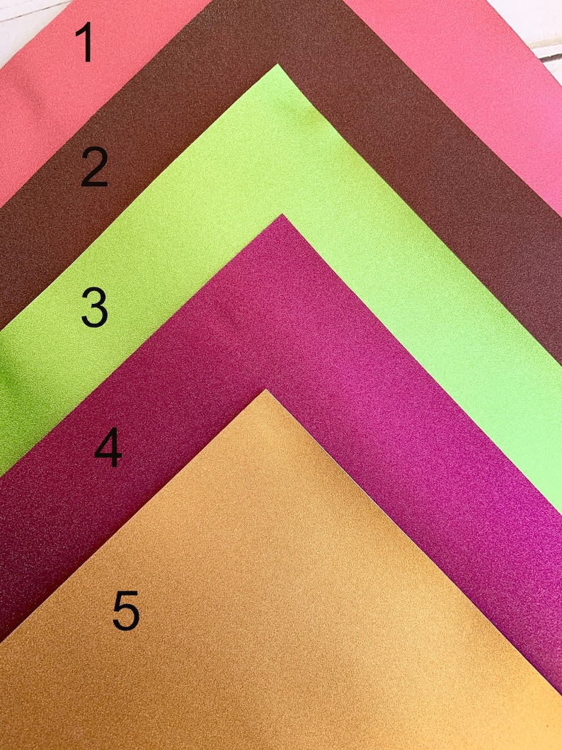 K&ouml;nnte beinhalten: F&uuml;nf unterschiedlich farbige Bl&auml;tter Papier, die in Form eines Dreiecks angeordnet sind. Die Farben sind Koralle, Limettengr&uuml;n, Burgunderrot, Gold und Braun. Die Zahlen 1 bis 5 sind auf der linken Seite jedes Blattes Papier geschrieben.