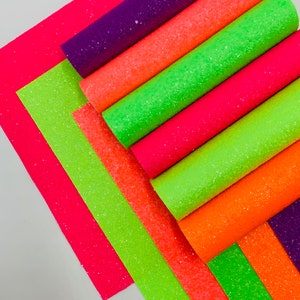 Pu&ograve; includere: Un set di otto fogli di tessuto glitterato in vari colori neon, tra cui rosa, arancione, verde e viola. Il tessuto &egrave; strutturato e ha una finitura scintillante.